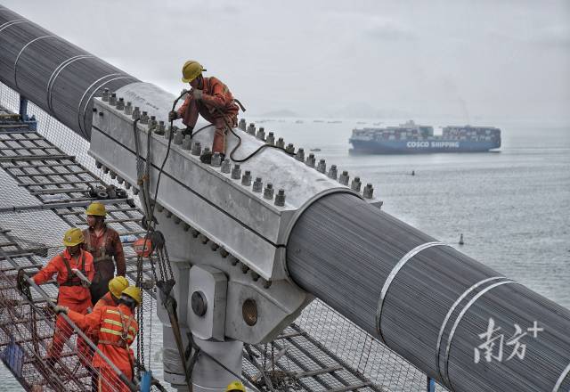 正在施工中的建設(shè)者身后，海上船舶往來不斷。  