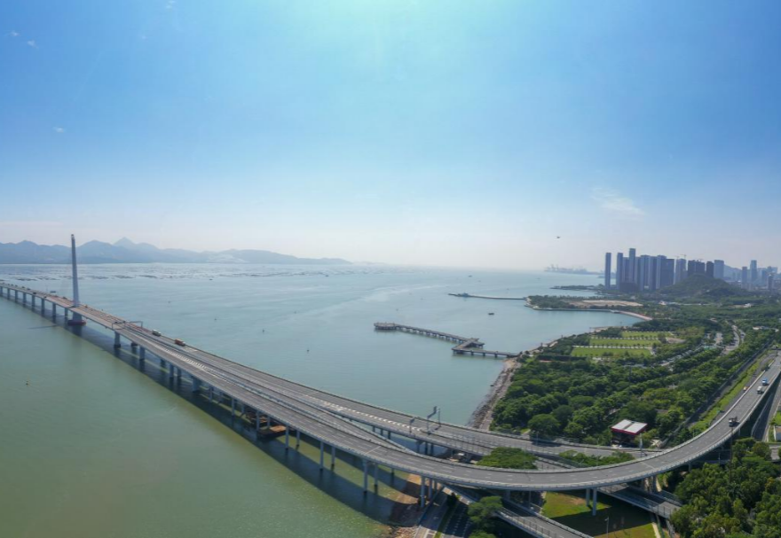 深圳灣大橋是繼羅湖、皇崗和沙頭角之后深圳第4條跨境通道，全長5545米，設(shè)南北兩個(gè)通航橋，主跨分別為210米和180米。大橋連接深圳蛇口與香港元朗，為中國公路干線網(wǎng)中唯一與香港連接的高速公路大橋，也是廣深沿江高速公路的咽喉。廣州與香港的距離因該橋建成通車縮短至100千米。大橋深圳側(cè)獨(dú)塔斜拉橋塔采用向香港側(cè)傾斜的斜塔，與香港側(cè)斜拉橋的橋塔向深圳側(cè)傾斜互相對(duì)應(yīng)，寓意深港兩地手牽手走向一起。圖為深圳灣大橋。