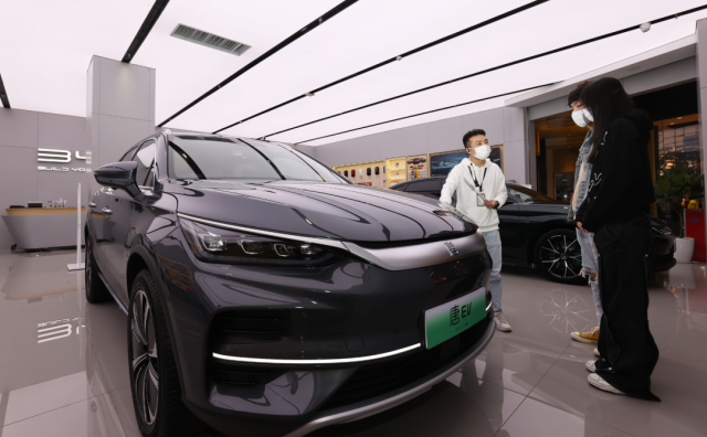 比亞迪店內，一名銷售人員（左）正在向兩位顧客介紹車輛信息。深圳特區(qū)報記者 楊浩翰 攝