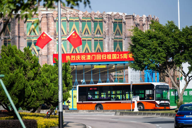 12月17日，車輛從慶祝澳門回歸祖國25周年橫幅旁駛過。新華社記者 朱煒 攝