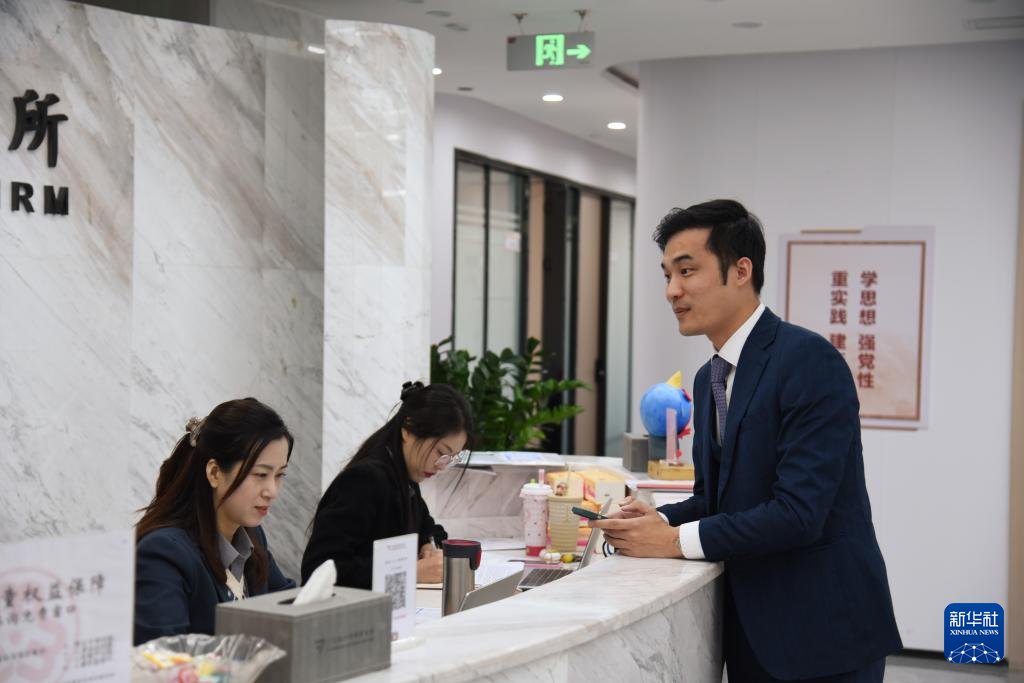 澳門律師阮嘉銳（右）在和同事交談（12月19日攝）。新華社記者 洪澤華 攝